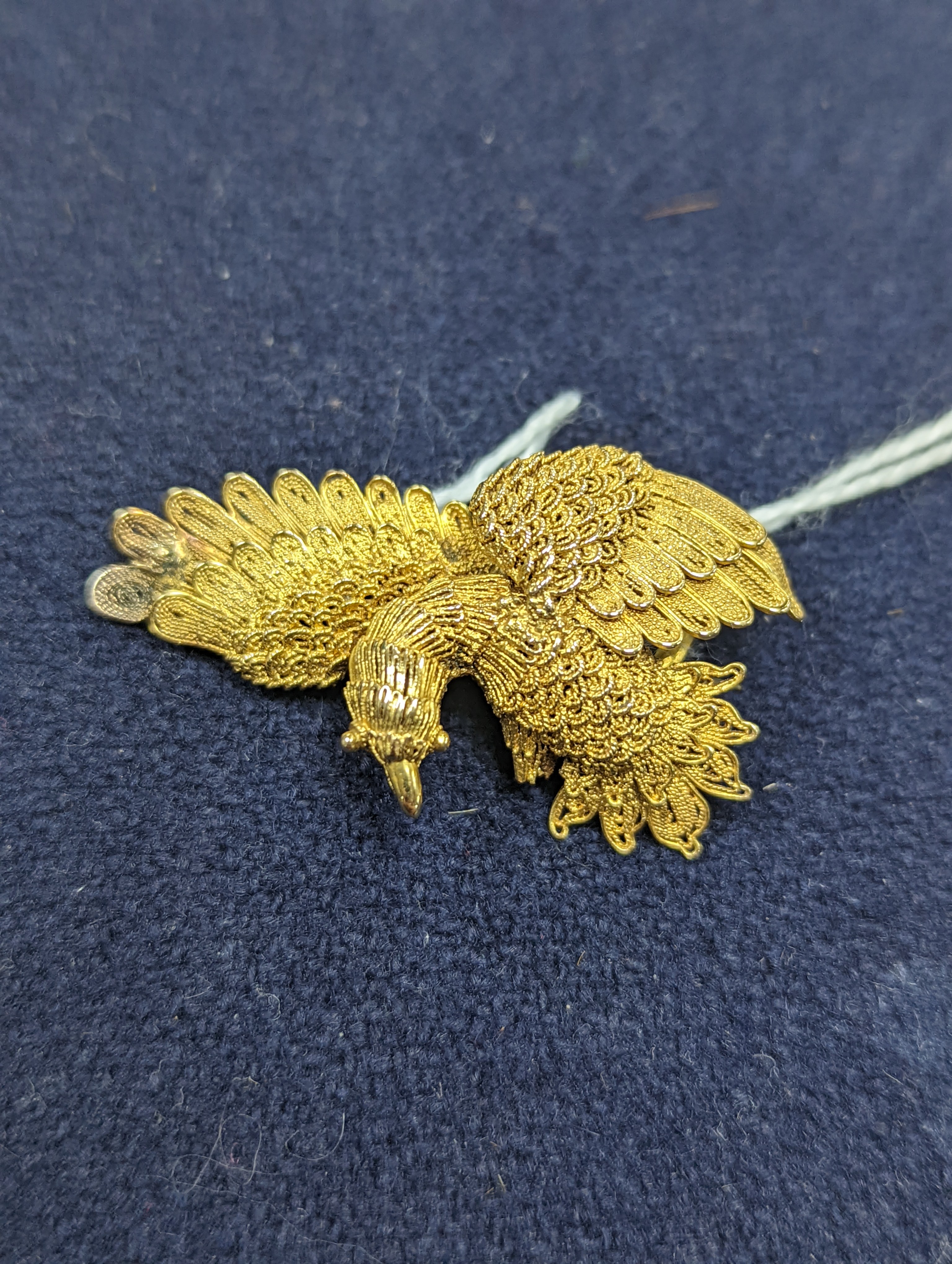 A Chinese filigree yellow metal eagle brooch, stamped 'WS 20 (with character marks)', 36mm, gross 6.5 grams.